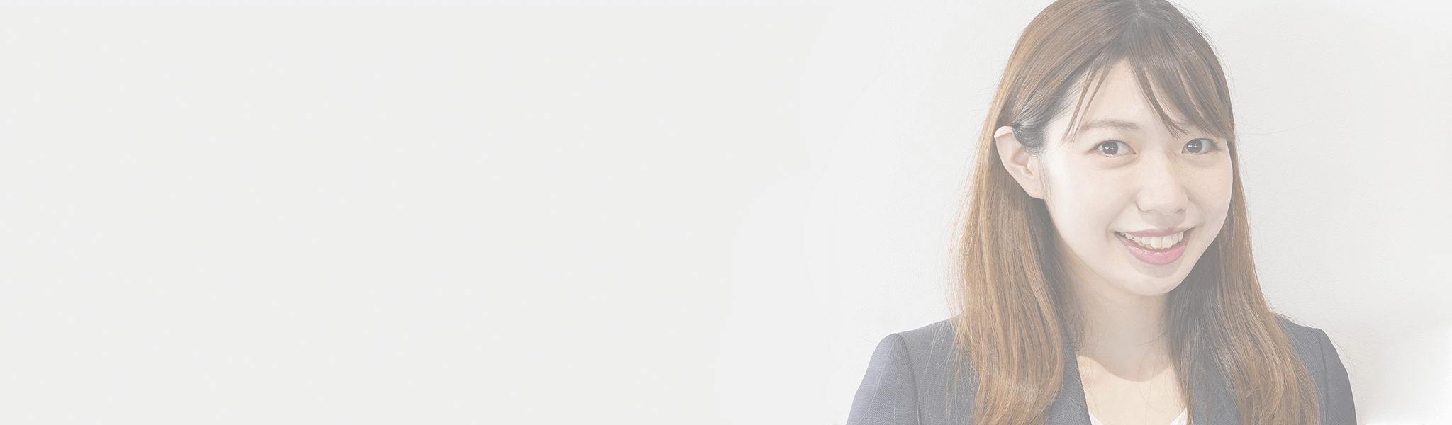 明るい白背景の右側に配置された、ネイビーのジャケットを着用した若い日本人女性の笑顔のクローズアップ写真。左側には広い空白スペースがあります。